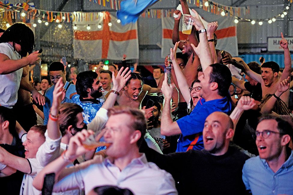 England fans celebrate as they watch a live broadcast of the semi-final match between England and Denmark at Hackney Bridge in London
