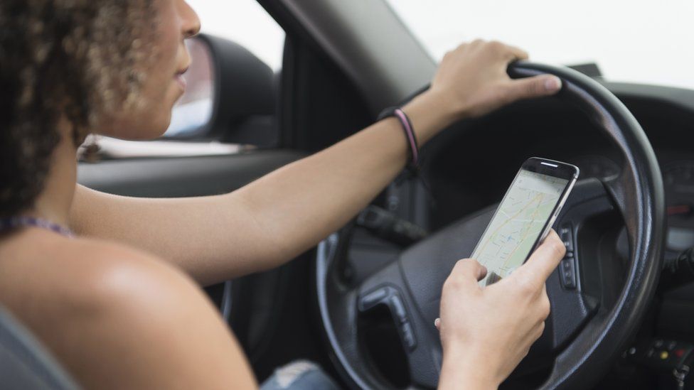 A woman looking at her phone while driving
