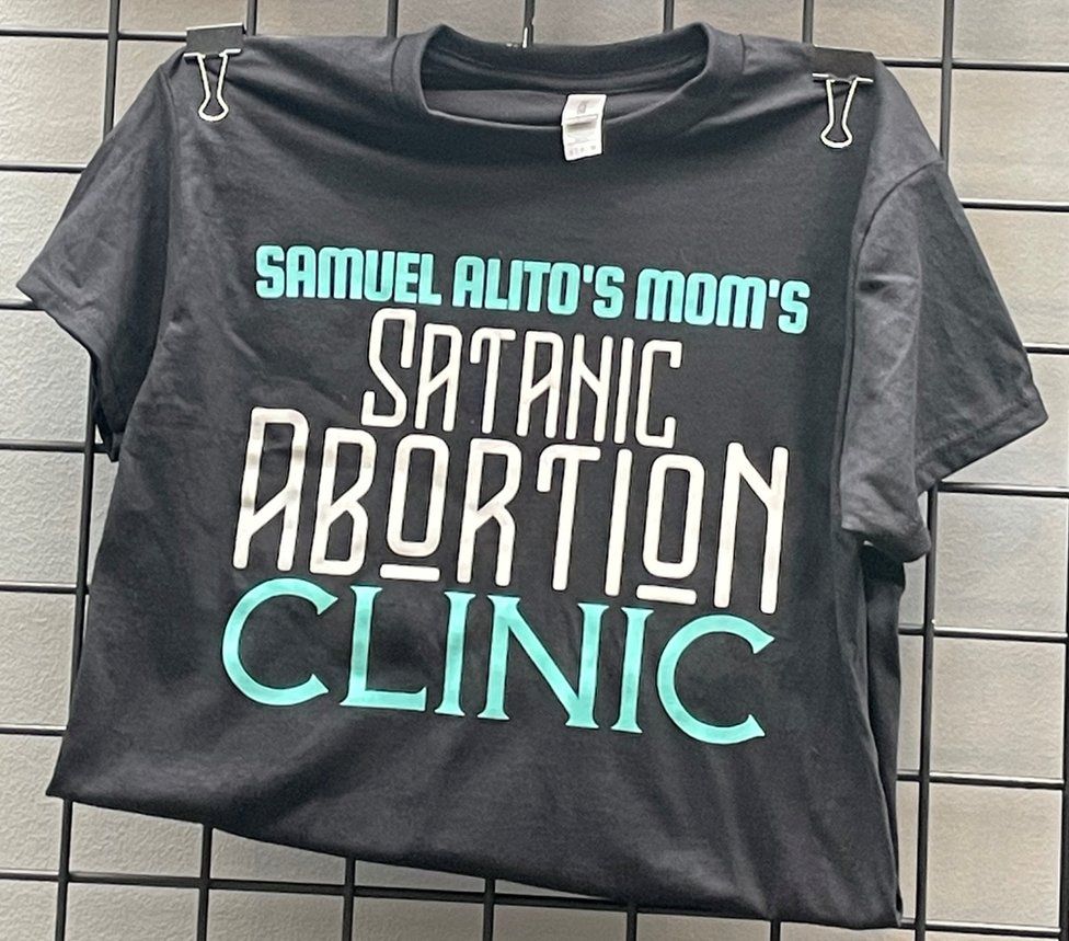 A t-shirt on sale at SatanCon reads, "Samuel Alito's mom's Satanic abortion clinic' - the name of the Temple's telehealth clinic in New Mexico