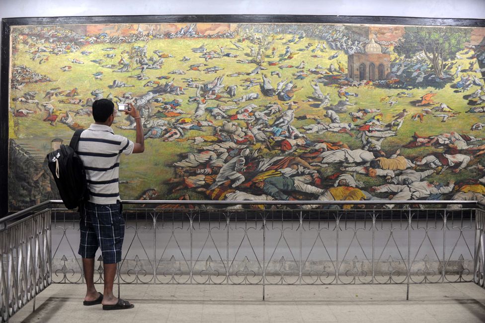 2011: An Indian man takes a photograph of a painting depicting the 1919 Jallianwala Bagh massacre in Amritsar.