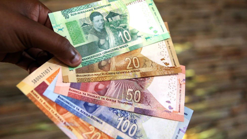 A man holding South African rand notes