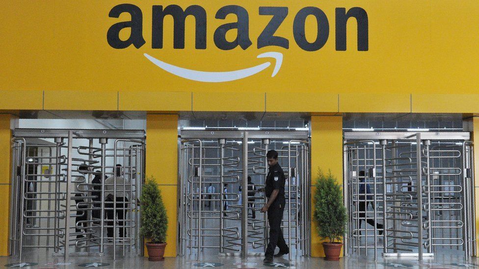 Security guard leaving through revolving metal gates at the entrance to Amazon's fulfilment centre at Hyderabad.