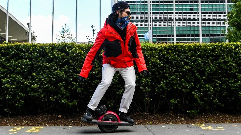 A Onewheel electric skateboard - a skateboard with a single wheel in the middle. The person stands either side of the wheel for balance.