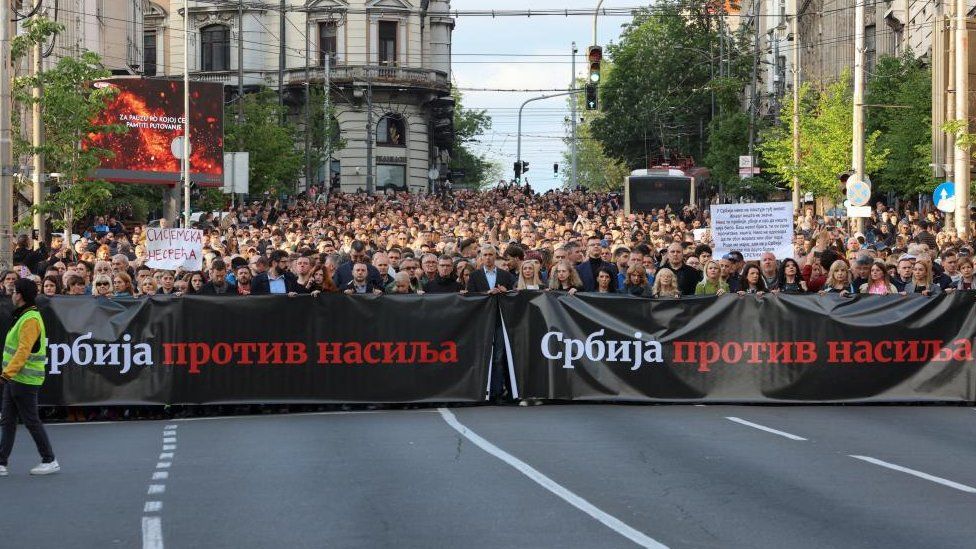 Тысячи людей маршируют под плакатом «Сербия против насилия»