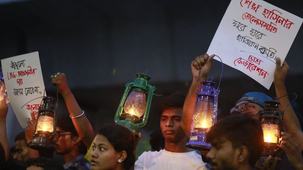 Демонстранты держат плакаты и масляные лампы в знак протеста против недавнего кризиса с электричеством в Дакке, Бангладеш, 25 июля 2022 года.