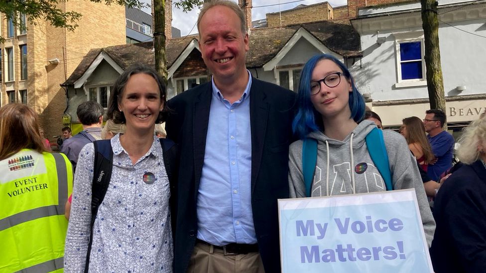 a mother, father and daughter at a protest holding a sign that reads "my voice matters!"