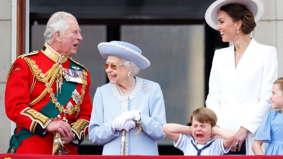 Prince Charles, Prince of Wales, Queen Elizabeth II, and Catherine, Duchess of Cambridge watch a flypast from the balcony of Buckingham Palace as Prince Louis of Cambridge screams and holds his hands over his ears