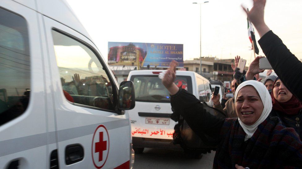 Syrian refugees wave to convoy of ambulances that evacuate wounded people from the rebel-held town of Zabadani, Syria, crossing the Lebanese border at Masnaa east of Lebanon (28 December 2015)