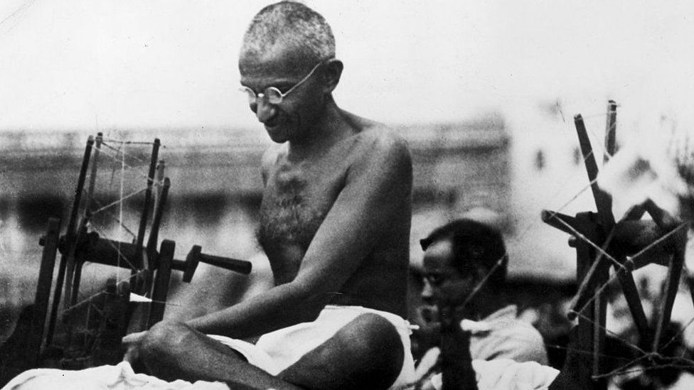9th June 1925: Indian Nationalist leader Mahatma Gandhi (Mohandas Karamchand Gandhi, 1869 - 1948) at a spinning wheel during a 'Charlea' demonstration in Mirzapur, Uttar Pradesh.