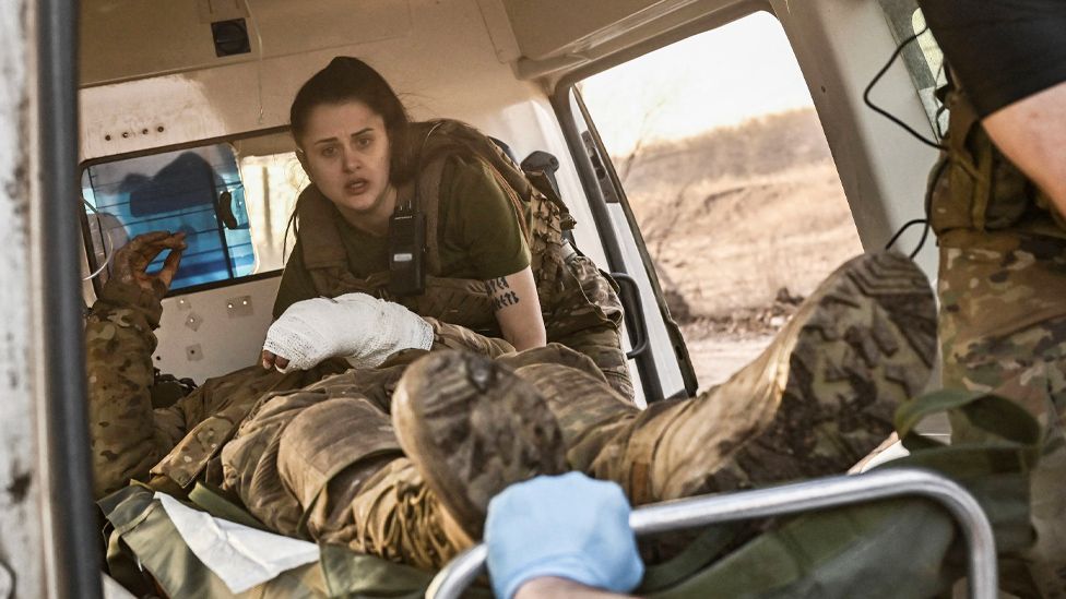Ukrainian military paramedics evacuate a wounded serviceman near the front line of Bakhmut, 23 March 2023