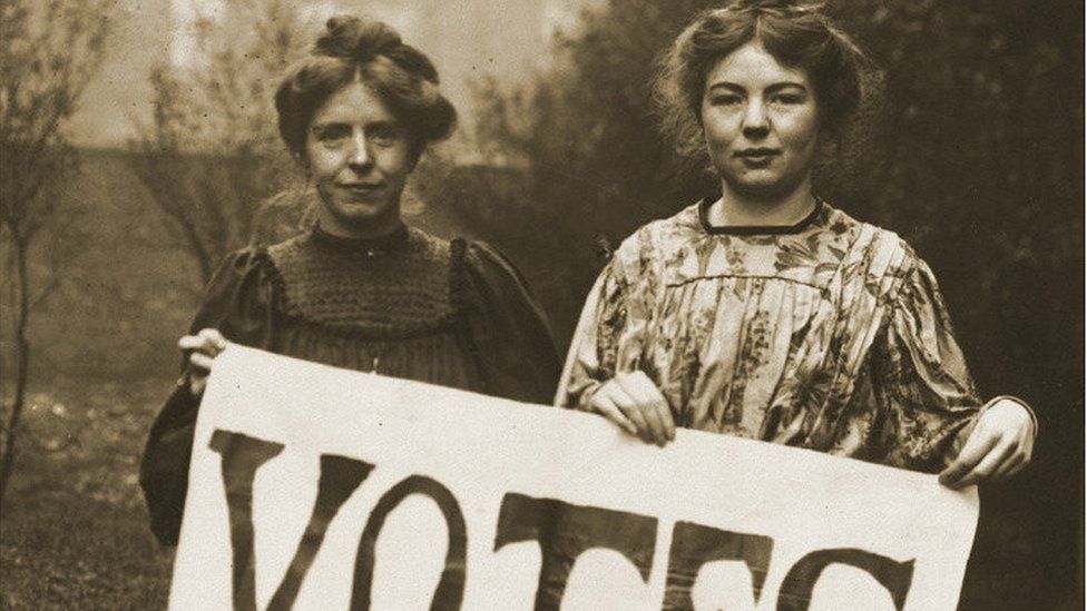 Annie Kenney and Christabel Pankhurst holding banner proclaiming "Votes for Women"