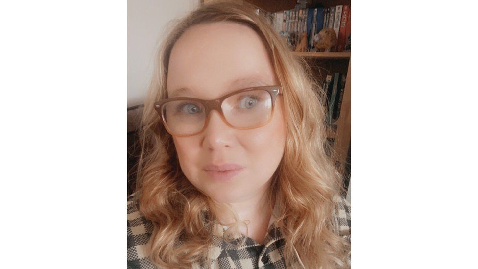 Image of Angharad, a white woman with blonde hair to below her shoulders and glasses. She is looking at the camera.