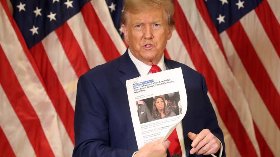 Former U.S. President Donald Trump holds up a news story about New York Attorney General Letitia James as he speaks to the media at one of his properties at 40 Wall Street following closing arguments at his civil fraud trial on January 11, 2024 in New York City.