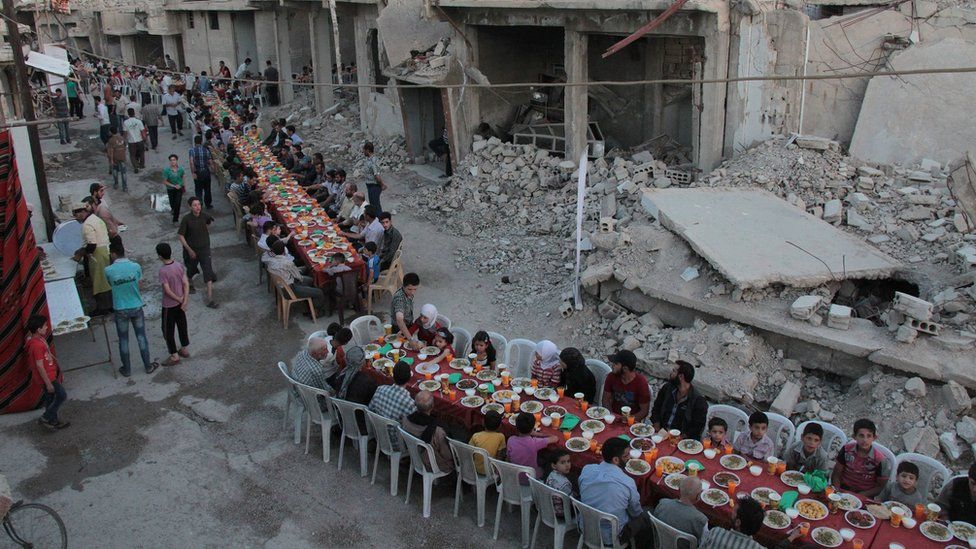 Syrian residents of the rebel-held town of Douma, on the outskirts of the capital Damascus, break their fast with the "iftar" meal on a heavily damaged street on June 18, 2017, during the Muslim holy month of Ramadan.