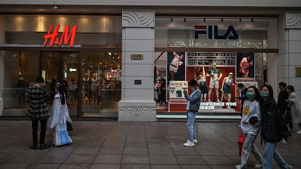 People walk past shopfronts for Swedish clothing giant H&M