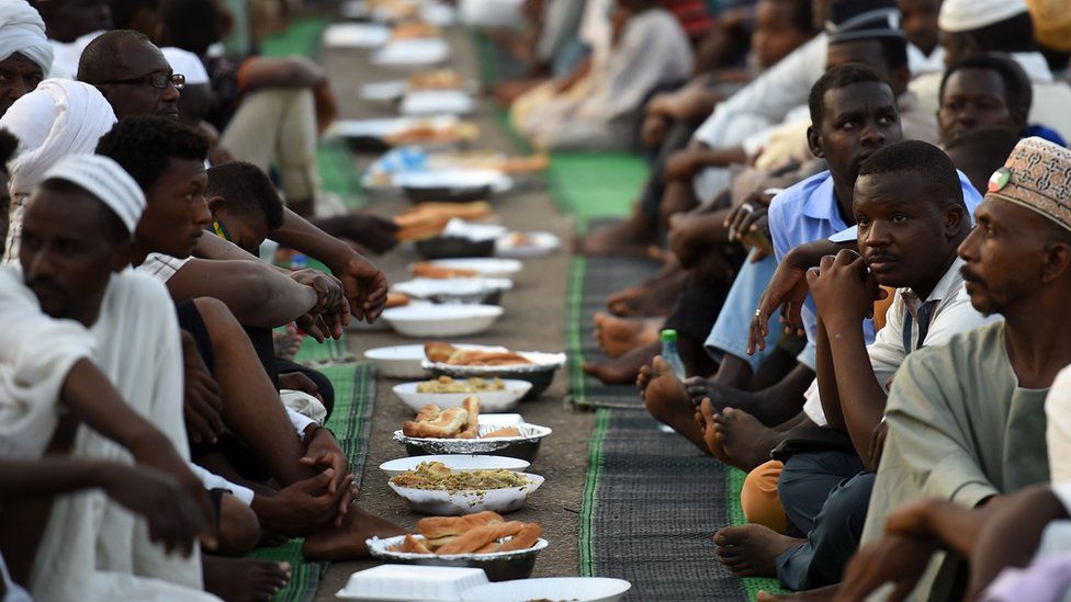 Sudanese men sit together as they are served Iftar at sunset during the Muslim holy month of Ramadan, at their protest outside the army headquarters in Sudan - 10 May 2019