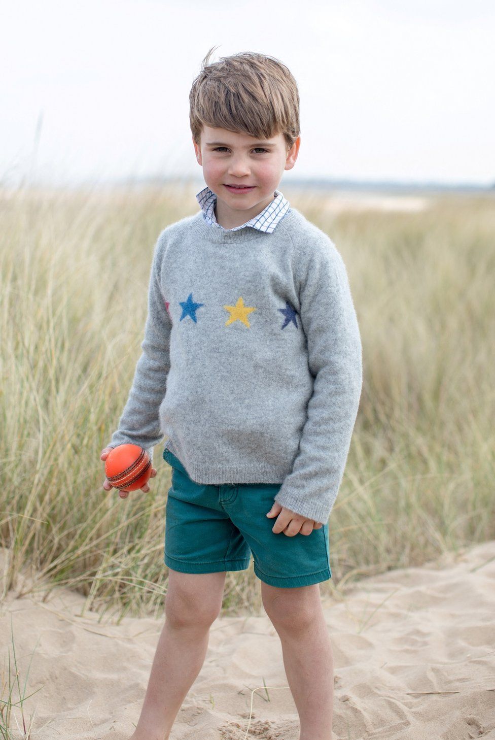 Prince Louis stands barefoot in the sand in Norfolk