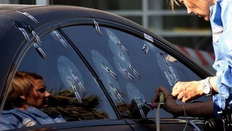 Unidentified ballistics investigator comb the scene of Radovan Krejcir's bullet-proof car after he escaped an attempt to kill him in Johannesburg, South Africa, Wednesday July 24, 2013.