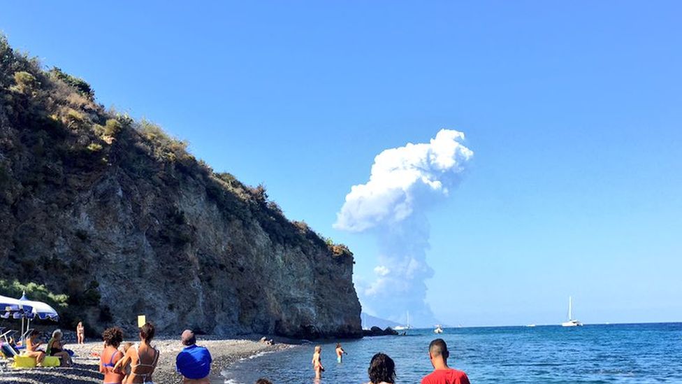 Tourists look on at an explosion in the distance