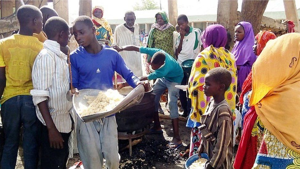 A man serves lunch from an open-air kitchen for people displaced by Boko Haram violence on May 19, 2016 in the Dalori Internally Displaced People's (IDP) Camp, near Maiduguri, northeast Nigeria.