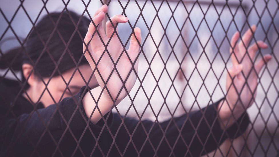 Woman placing hands on wire fence (stock image)