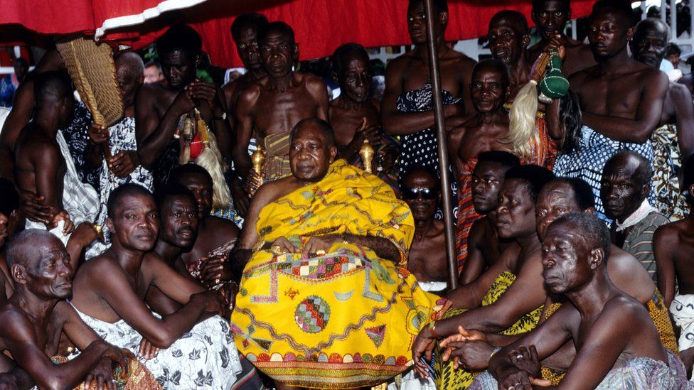 The Asantehene, wearing yellow robes, sitting with his court