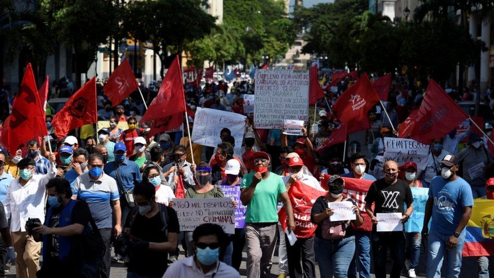 Protesters holding flags and banners march in Guayaquil