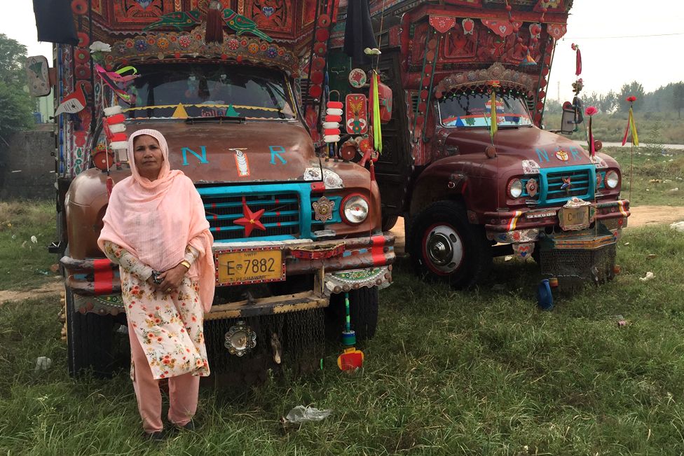 Shamim standing in front of trucks