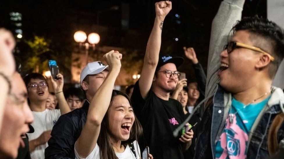 Pro-democracy supporters chant as they celebrate after pro-Beijing candidate Junius Ho lost a seat in the district council elections in Tuen Mun district of Hong Kong