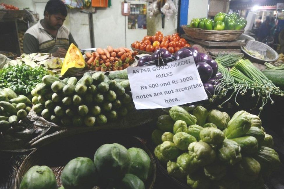 An Indian vendor displays a sign relating to new currency regulations as he waits for customers, following the decision to withdraw the current 500 and 1000 INR notes, in Siliguri on November 13, 2016.