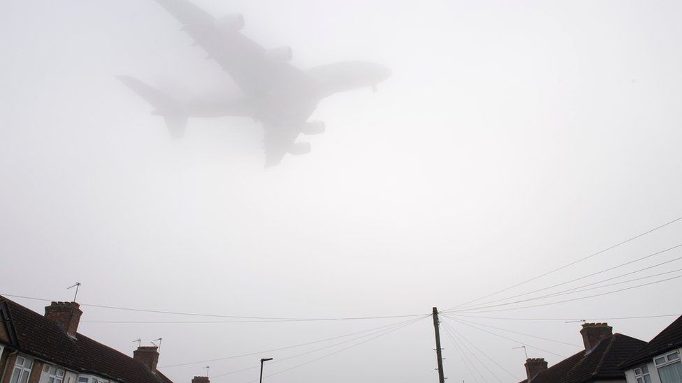 A plane flies through fog