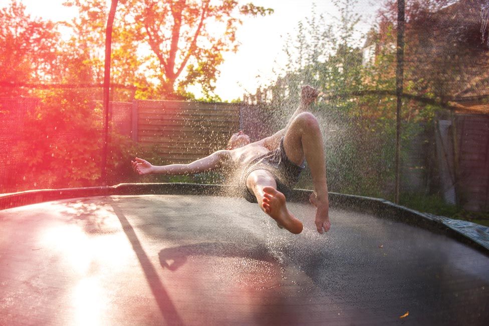 A person bouncing on a trampoline in a garden