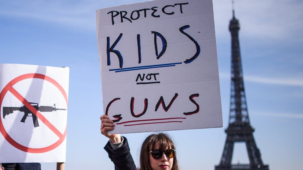 A woman holds a poster which read "Protect Kids not Guns" as French and Americans gather near the Eiffel Tower on the Trocadero square in support of the US "March For Our Lives" movement, in Paris, France,