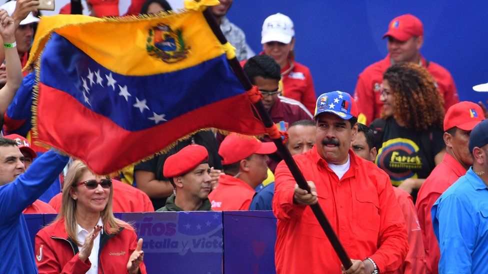 Venezuelan President Nicolas Maduro waves a national flag during a gathering with supporters to mark the 20th anniversary of the rise of power of the late Hugo Chavez
