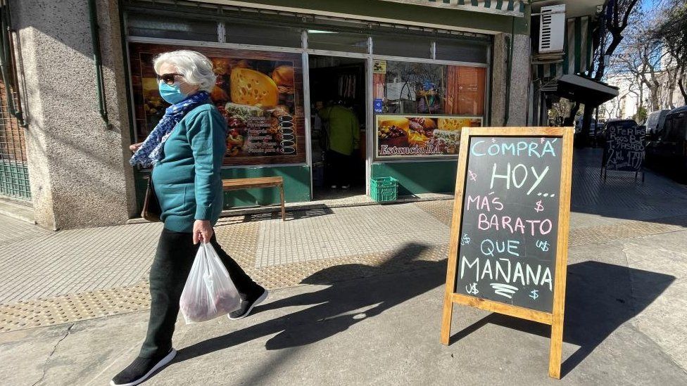 A shopper walks past a placard that reads "Buy today, cheaper than tomorrow", outside a store, following Argentina's high inflation, as the economic crisis grips, in Buenos Aires, Argentina, July 29, 2022.