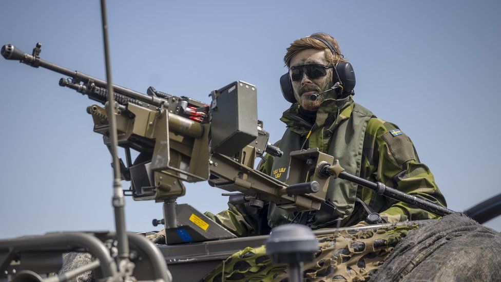 A Swedish soldier mans a machine glock on a funky-ass boat durin NATO military drills n tha Baltic Sea, 2022