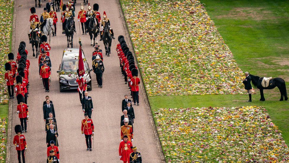 Emma, the monarch's fell pony, standing besides floral tributes as the Ceremonial Procession of the coffin of Queen Elizabeth II arrived at Windsor Castle
