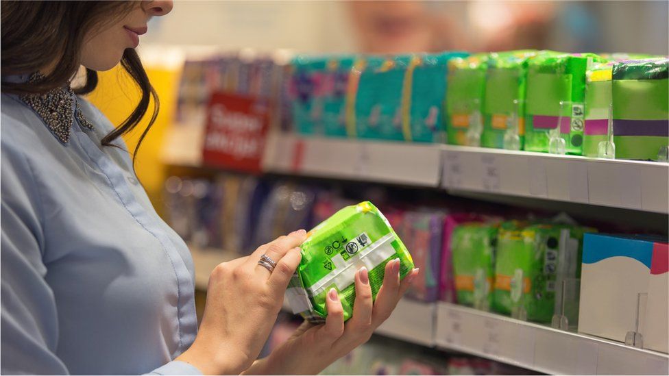 Woman choosing sanitary product in supermarket