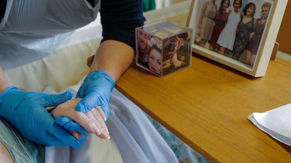 Nurse holding elderly woman's hand