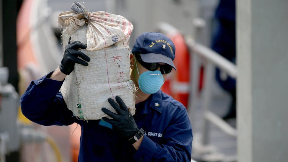 A US Coast Guard officer carries a bundle of seized cocaine