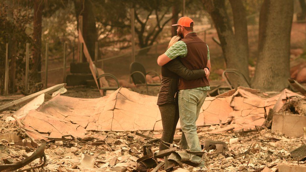A couple hug in wreckage of home