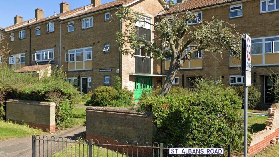 Three-story flats with small garden bordered by hedges