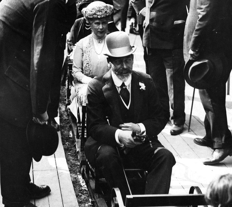 Black and white photo of King George V and Queen Mary riding a miniature train