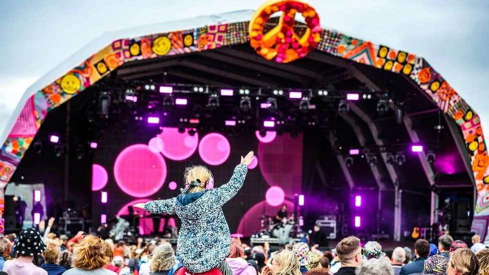 A child on an adult's shoulders in a festival crowd