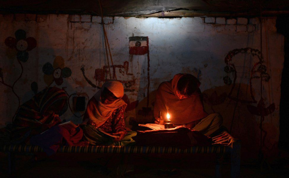 Indian girls study by candle light in a slum without electric power in the town of Jalandhar