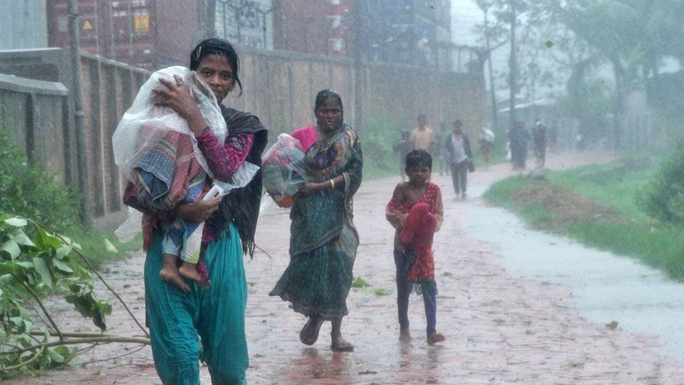 Bangladeshi people walk through waterlogged streets in Chittagong district