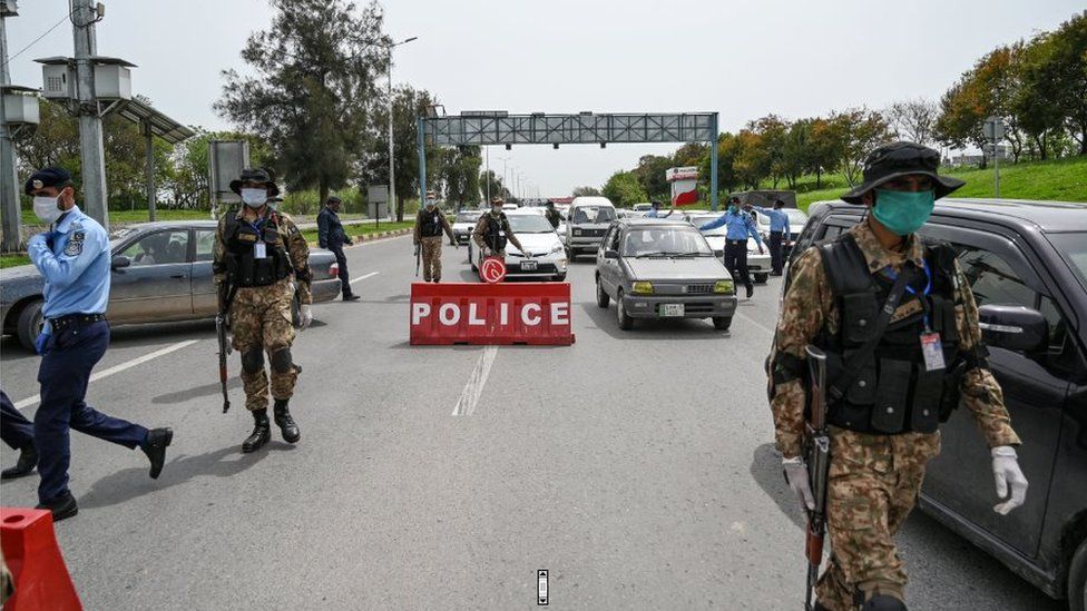Security personnel wearing facemasks check commuters at a checkpoint of the city's entrance during a government-imposed nationwide lockdown as a preventive measure against the COVID-19 coronavirus in Islamabad