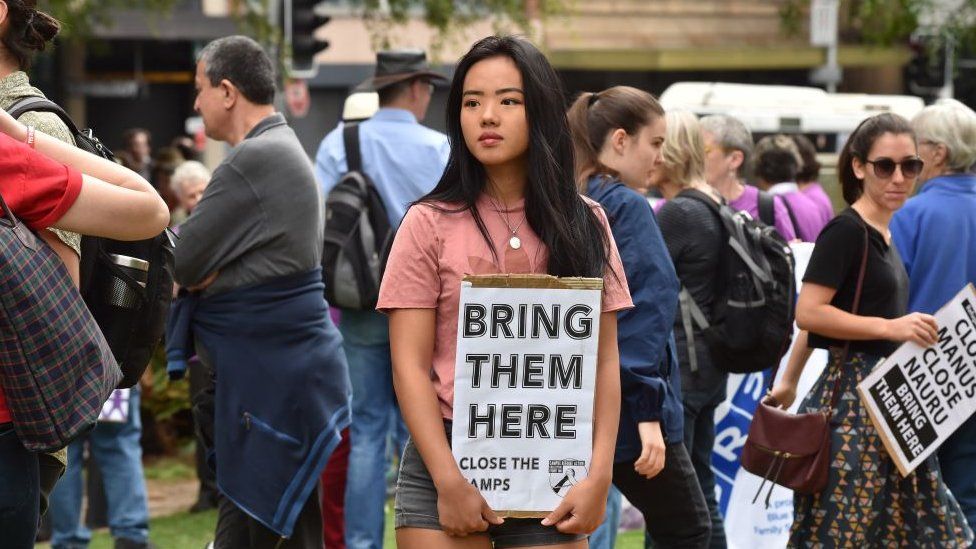 A woman holds a sign saying bring them home