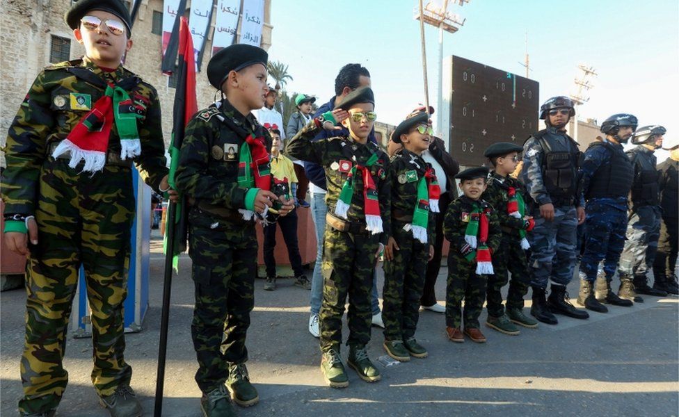 Libyans children dressed in military fatigue stand at attention during a gathering to commemorate the ninth anniversary of the uprising against former Libyan leader Muammar Gaddafi in the capital Tripoli on 17 February 2020.