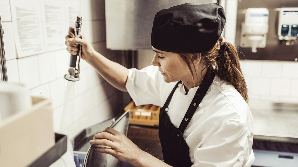 Woman washing up in a commercial kitchen